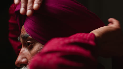 Close-Up-Low-Key-Studio-Lighting-Shot-Of-Senior-Sikh-Man-With-Beard-Tying-Fabric-For-Turban-Against-Dark-Background-3